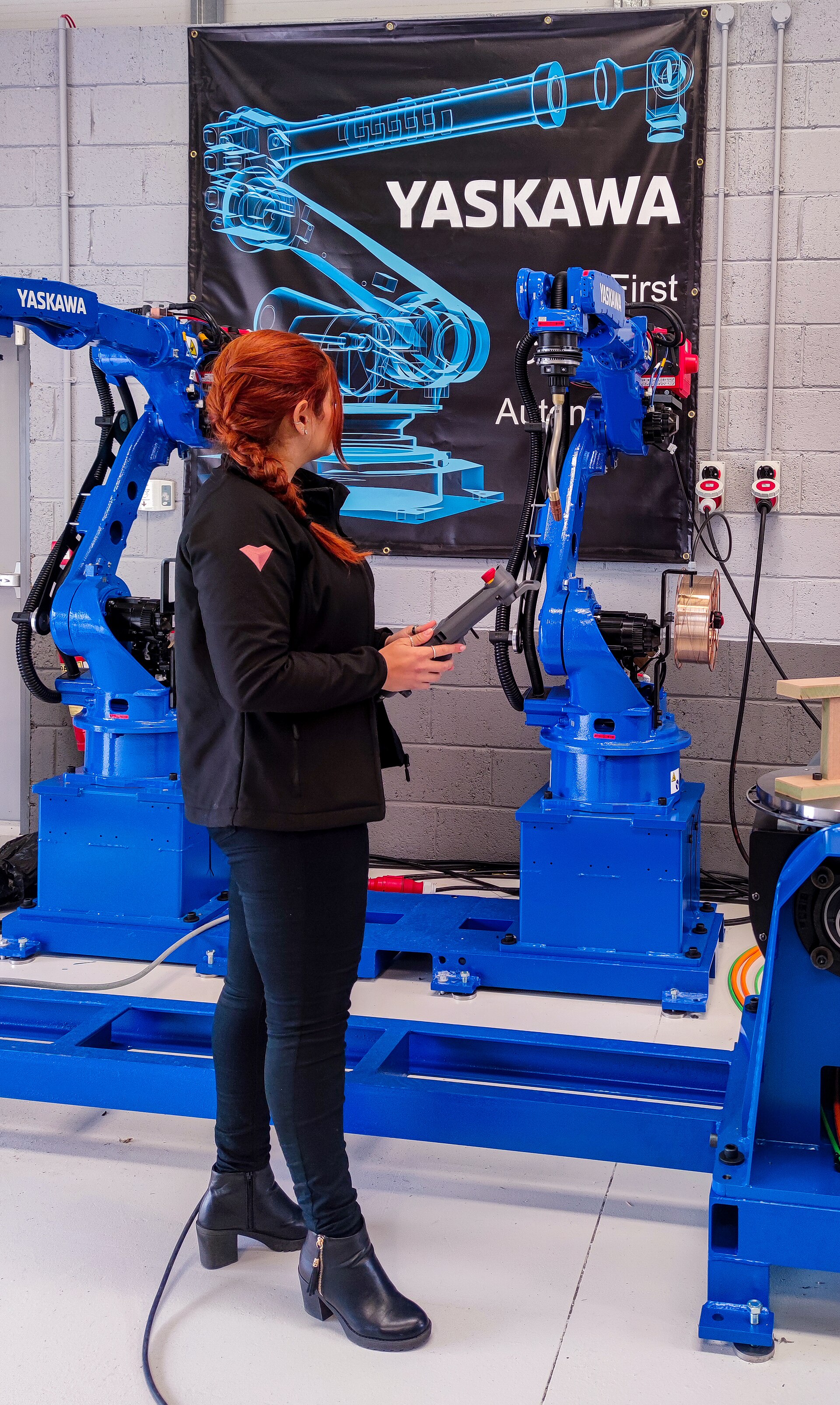 Person standing beside a Yaskawa industrial robot in a workplace