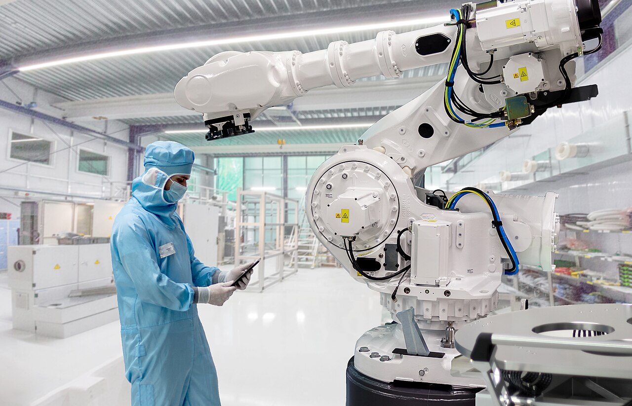 Field-service engineer working beside an ABB industrial robot in a German cleanroom